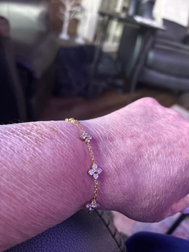 Close-up of a customer wearing the gold Lumi Clover Bracelet with glittering charms on their wrist.