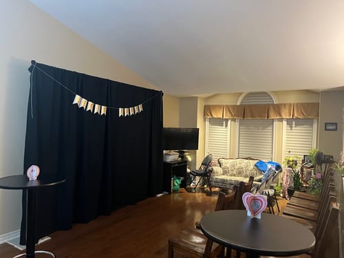 Customer's living room set up with a black curtain backdrop and tables for the murder mystery game.