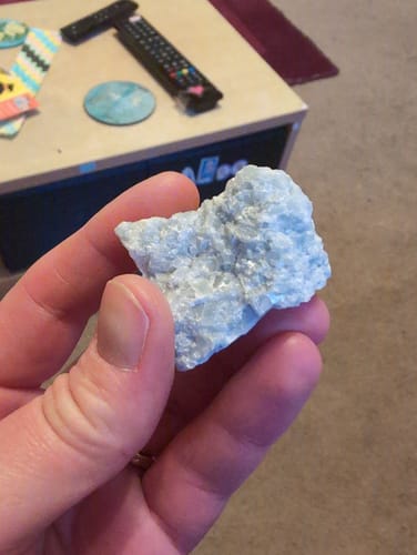 Reviewer holding the raw, light-blue monthly crystal from their VIP Crystal Club subscription.