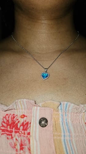 A reviewer wearing the Silver Titanic Heart Of The Ocean Pendant, which rests just below their collarbone.