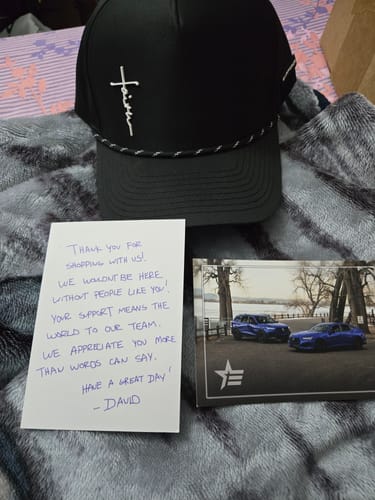 Customer's black Faith Snapback displayed with a handwritten thank-you note and card from the seller.