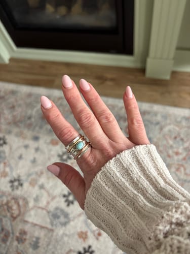 Customer's hand wearing the wide Sterling Silver Two Tone Spinner Larimar Ring indoors.