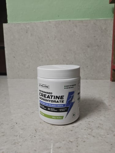 Reviewer's white tub of Wellcore Micronised Creatine Monohydrate sitting on a light-colored tiled surface.