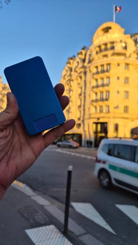 Customer holding a blue metal pill case from the 2-Pack Bundle on a street in Paris.