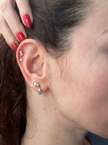 Customer showing the dainty Dangle flatback stud in their cartilage piercing, holding back their hair.