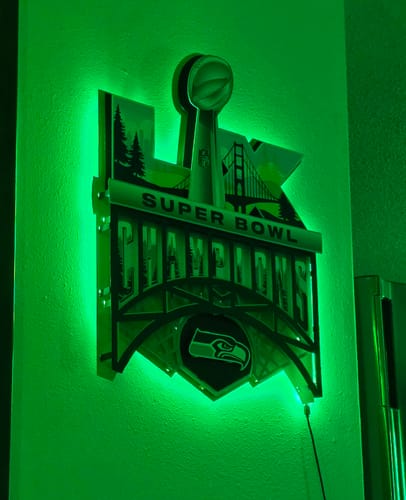 Reviewer's Seattle Seahawks 3D metal wall art mounted on a wall and glowing with green LED backlighting.