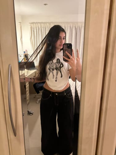 Reviewer taking a mirror selfie while wearing the white after party baby tee with dark pants.