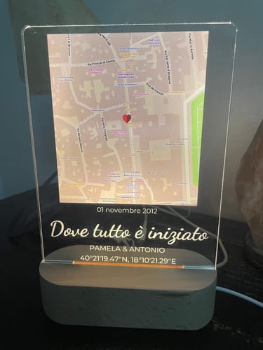 Kundenfoto des personalisierten Nachtlichts. Es zeigt eine beleuchtete Karte und Gravur auf einem Holzsockel.