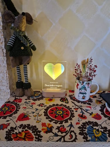 Kundenfoto des personalisierten Nachtlichts mit Holzsockel, das auf einem bunten Tischtuch leuchtet.