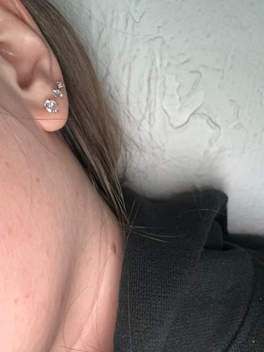 Ein Kunde trägt drei glänzende Bright Diamond Ohrstecker in einer Reihe am Ohr.