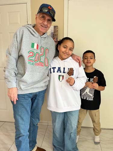 Customer wearing the grey Milano Cortina 2026 Hoodie while standing with two children.