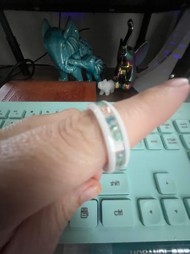 Close-up of a reviewer wearing the white cremation ring with a beautiful blue and green glass inlay.