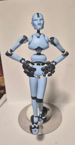 Customer's light blue Stickybones figure in a confident pose with hands on hips, standing on its round metal base.