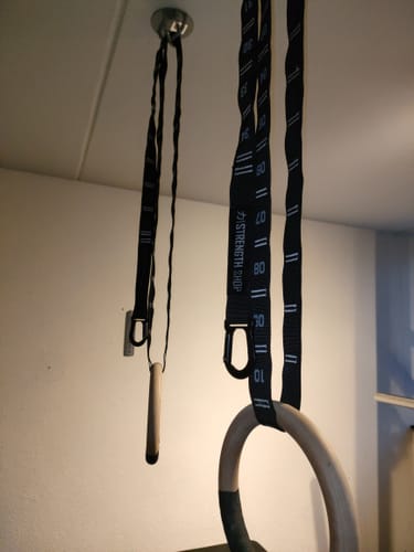 Customer's wooden Gymnastic Ring on a numbered strap with a carabiner, hanging from the ceiling.