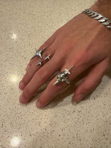 Customer wearing the silver NIGHTMARE RING, featuring a skull and sword, on their hand with other rings.