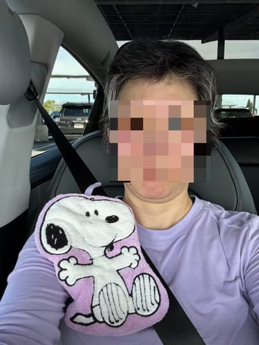 Customer holding the purple Snoopy-shaped hand towel while sitting in a car.