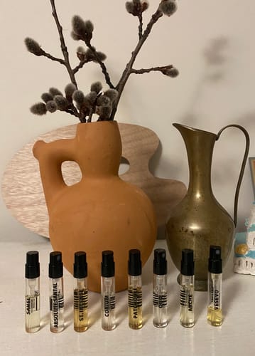 Recensore mostra gli 8 campioni di profumo del set orientale e legnoso, disposti in fila su un tavolo.