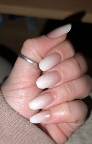 Nahaufnahme der Hand einer Kundin, die lange, ovale Nägel mit dem 'Babyboomer Nude' UV-Gel trägt.
