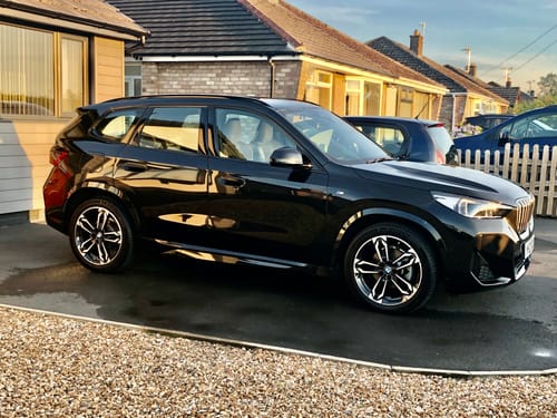 Reviewer's shiny black car parked on a driveway, showing the results of Champs Luxury Shampoo.
