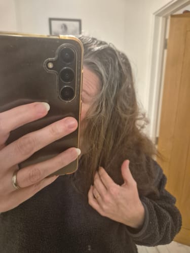 A reviewer shows their hair, with visible grey roots, before using the Instant Dye Shampoo.