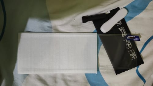 Customer displays the UltraShield Tempered Glass and its installation kit before application.