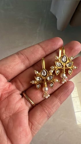 Customer's hand holding the pair of 22k Gold Plated Earcuffs with kundan stones and freshwater pearl drops.