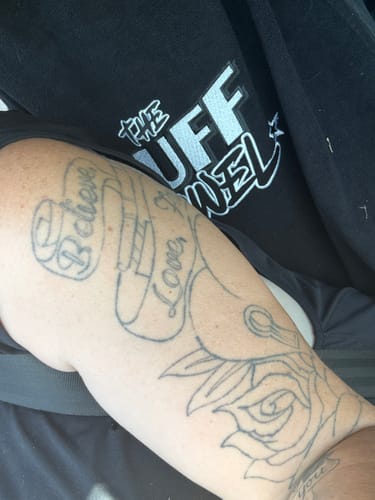 Close-up of a reviewer's black Tuff Towel car seat cover with the logo partially visible behind their arm.