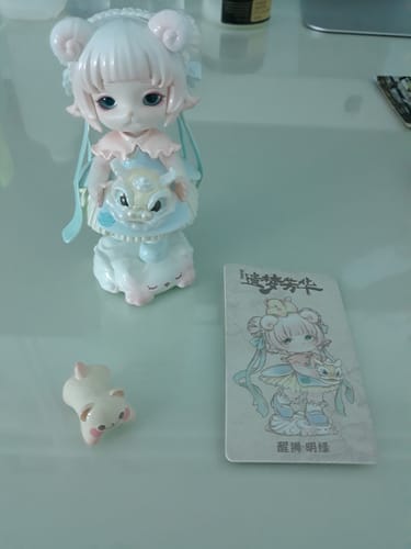 Reviewer's pastel Mimia Art of Forgotten Dream figure, its small accessory, and character card on a table.
