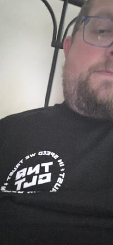 Close-up of a reviewer wearing the black MYSTERY TEE with a white graphic logo on the chest.