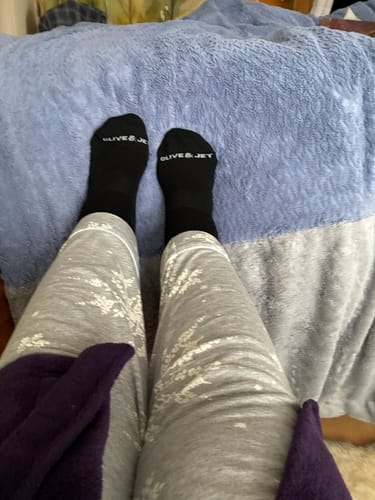 Reviewer wearing soft, black Quarter Socks with feet propped on a blue blanket.