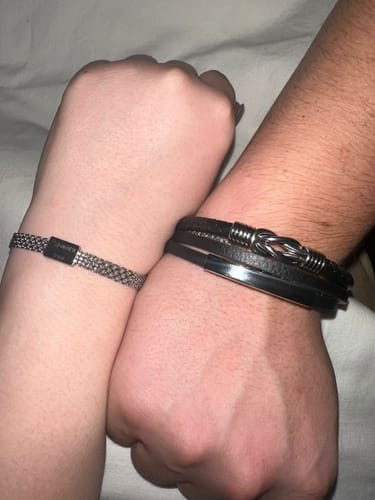 Customer showing their black leather Bond bracelet with an intertwined knot on their wrist, next to another person.