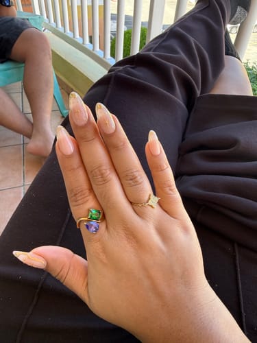 Customer's hand wearing the Navae Birthstone Ring with vibrant green and purple stones.