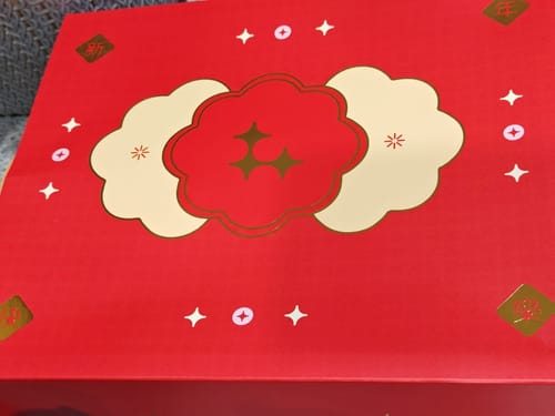 Reviewer's close-up of the Golden Radiance Bundle's festive red and gold gift box packaging.