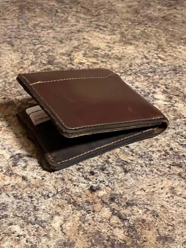 Customer's brown leather Tahoe Bifold wallet on a countertop, slightly open to show its sturdy thickness.