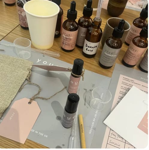 Customer's view of the Perfume Making Workshop with essential oil bottles, mixing tools, and two finished roll-on fragrances.