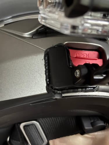 Close-up of a reviewer's black Shoei Neotec 2 Camera Mount sealed with silicone on a grey helmet.