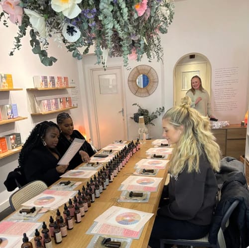 Customers at a long table during the Perfume Making Workshop, with numerous essential oil bottles ready for blending.