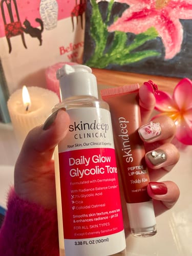 Reviewer's hand holding the Peptide Lip Glaze tube alongside another skincare bottle.