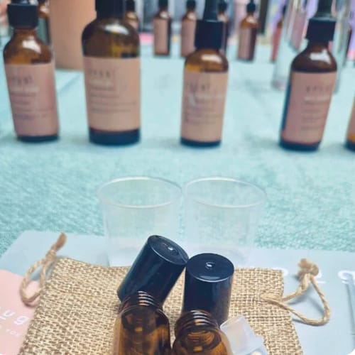 Customer's close-up of the Perfume Making Workshop setup, showing amber bottles, measuring cups, and a burlap pouch.
