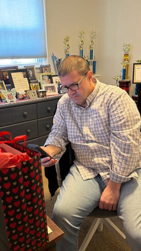 Customer's husband looking at his phone, watching the 'Your Song On YouTube' video gift he received.