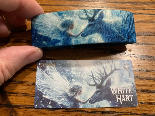 Customer holding the Goldie Mystery ZOX wristband with its white stag design above the matching art card.