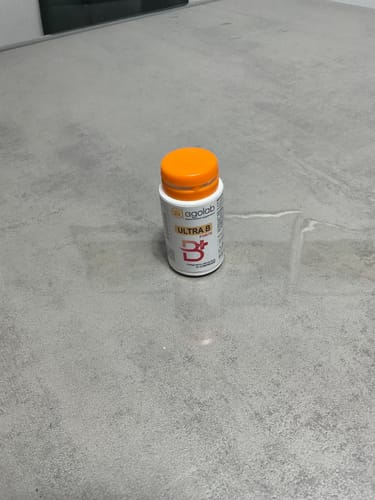 Il cliente mostra il flacone bianco di Ultra B Forte con il suo tappo arancione su un ripiano grigio.