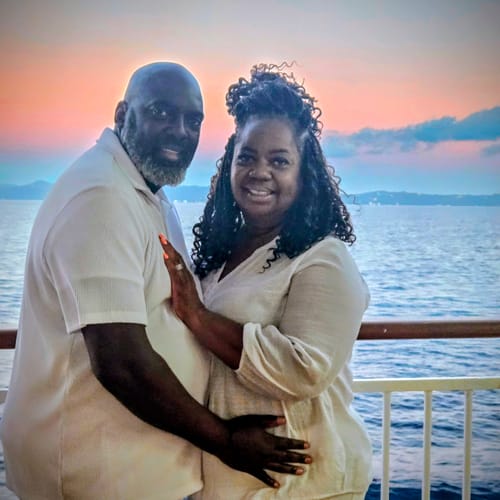 Customer and her husband embracing happily by the sea, thrilled with their 'Your Song On YouTube' gift.