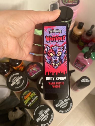 Customer holding a bottle of Werewolf Body Spray in front of other body care products on a shelf.