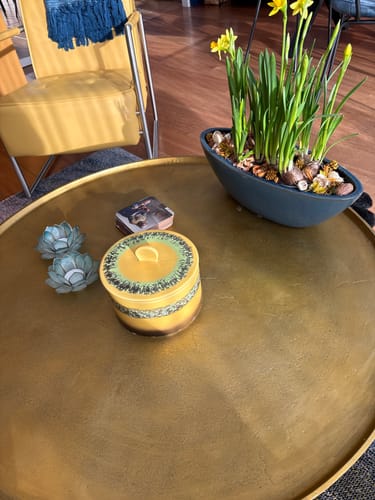 Klant toont de kleurrijke HKliving 70's koekjestrommel op een gouden salontafel in de woonkamer.