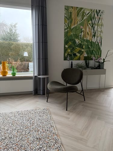 Klant toont de MISOU bijzettafel naast een moderne stoel in de woonkamer.