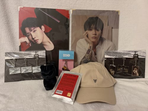 A customer's merchandise from the BTS K-POP Random Box, showing photos of j-hope and Jung Kook, a V cap, and keychains.