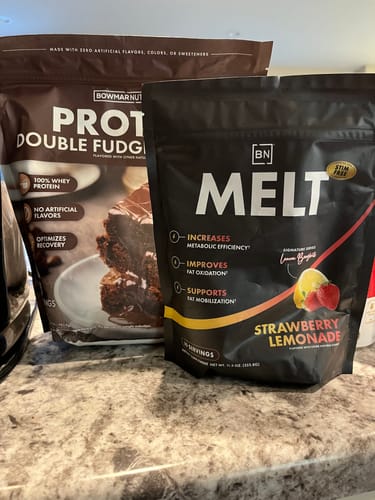 Customer's bag of Double Fudge Whey Protein sitting on a counter next to a bag of Strawberry Lemonade Melt.