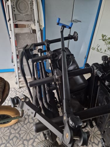 Beoordelaar toont een detailopname van het zwarte POLE SUPPORT SYSTEM met de blauwe EVA-steun gemonteerd op een visstoel.