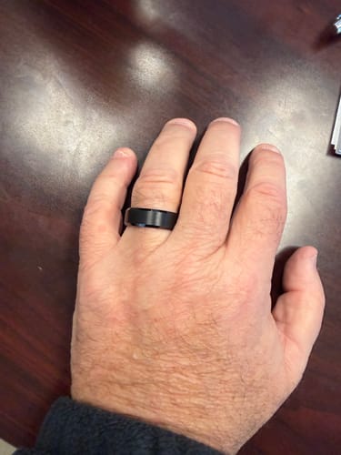 Customer showing their black Odin ring on their hand against a dark wooden table.